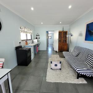 ein Wohnzimmer mit Couch und Küche in der Unterkunft Shell Cottage a stone's throw from the beach in Langebaan