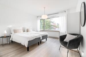 ein weißes Schlafzimmer mit einem Bett und einem Stuhl in der Unterkunft Cosy flat with good transport connections in Vantaa