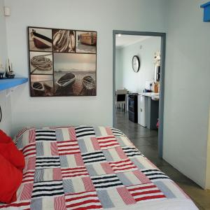 Schlafzimmer mit einem Bett und einer Tür, die zu einer Küche führt in der Unterkunft Shell Cottage a stone's throw from the beach in Langebaan