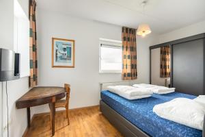 Dormitorio con cama, escritorio y TV en Hello Zeeland - Appartement Port Scaldis 19-031, en Breskens