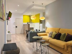 バルセロナにあるStay U-nique Apartments Santsのリビングルーム(黄色のソファ付)、キッチンが備わります。