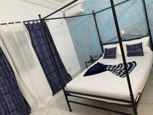 - une chambre avec un lit à baldaquin et des murs bleus dans l'établissement La Villeneuvoise, à Mbour 92 autres photos