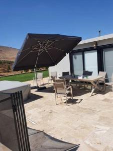 eine Terrasse mit einem Tisch, Stühlen und einem Sonnenschirm in der Unterkunft זריחה למרגלות הגלבוע in Nurit