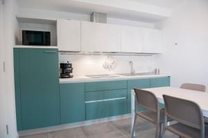 a kitchen with blue cabinets and a table with chairs at Lough appartamento in Colà di Lazise