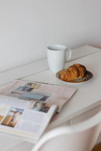 a table with a cup of coffee and a plate of bread at Spacious Apartment Pałac Jana III Wilanów by Renters in Warsaw