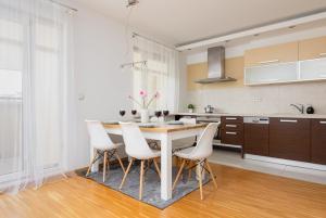 a kitchen with a wooden table and white chairs at Spacious Apartment Pałac Jana III Wilanów by Renters in Warsaw