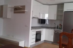a kitchen with white cabinets and stainless steel appliances at APART-DUPLEX-ATICO Tomares in Tomares