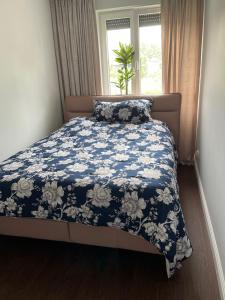 a bed with a blue and white comforter and a window at Luxury Maślice Apartment in Wrocław
