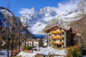 uma casa de montanha com montanhas cobertas de neve ao fundo em Hotel Aigle em Courmayeur