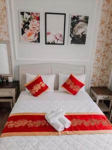 um quarto com uma cama com almofadas vermelhas e brancas em thiên phú hotel em Ho Chi Minh