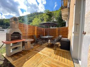 un patio con parrilla, mesa y sombrilla en Sauna en bord de rivière, en Morez