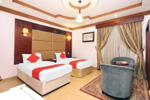 una habitación de hotel con 2 camas y una silla en OYO 589 Lavina House en Yeda