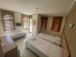 a room with two beds and a table and windows at Astoria Beach Hotel in Marmaris