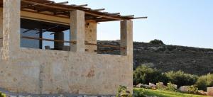 une maison en pierre avec une fenêtre sur une colline dans l'établissement Alagni Cretan Resort, à Stíronas