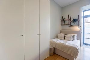 een slaapkamer met witte kasten en een bed bij 31 Janeiro 157 - Stylish 1BR w/ AC & Balcony by LovelyStay in Porto