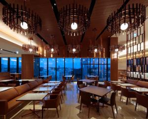 een restaurant met tafels en stoelen en kroonluchters bij Candeo Hotels Kumamoto Shinshigai in Kumamoto