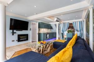 ein Wohnzimmer mit einem blauen Sofa und einem TV in der Unterkunft LUXURY BEACH PROPERTY- Neptune's Nest in Sandgate