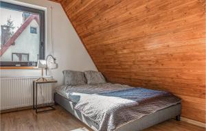 a bed in a room with a wooden wall at Lovely Home In Brenna With Kitchen in Brenna