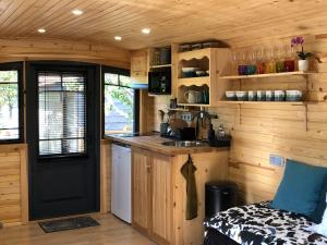 a kitchen in a tiny house with a black door at Roulotte Gîtes O bien-être massage Spa Séjour bien-être en hébergement insolite roulotte Karantez ou en gîtes Melon ou Yock à 800 m des plages Maison d'hôte Drogou in Porspoder