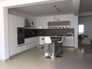 a white kitchen with a counter and stools in it at THE ONE - 4 Bedroom St Julian’s in St. Julianʼs