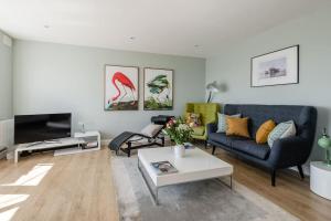 a living room with a blue couch and a table at Spacious and luxe two king bedroom sea-view apt in Brighton & Hove