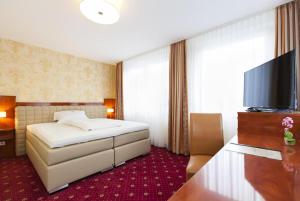 a hotel room with a bed and a flat screen tv at Hotel am Berliner Platz in Langenfeld