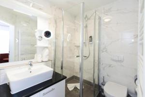 a white bathroom with a sink and a shower at Hotel am Berliner Platz in Langenfeld