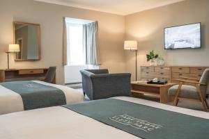 a hotel room with two beds and a desk at Aberystwyth Park Lodge Hotel in Aberystwyth