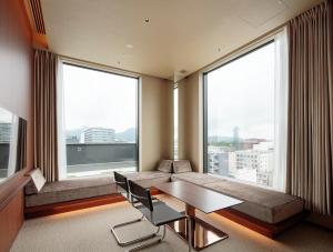 um quarto de hotel com uma mesa e cadeiras e janelas grandes em Candeo Hotels Kumamoto Shinshigai em Kumamoto