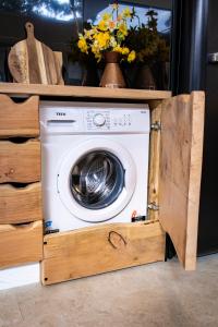 a washing machine in a wooden cabinet with flowers at Bruny Island Oceanfront Luxe Cabin with Spa in Adventure Bay +37 photos
