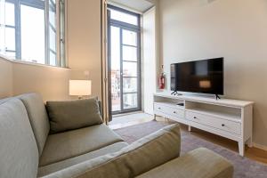 een woonkamer met een bank en een flatscreen-tv bij 31 Janeiro 157 - Delightful 1BR Flat w/ AC & Balcony by LovelyStay in Porto