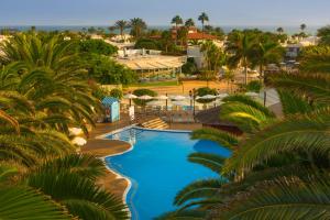 an aerial view of a resort pool with palm trees at Alua Suites Fuerteventura in Corralejo