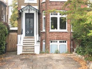 uma casa de tijolos com uma porta azul e um alpendre em East Finchley N2 apartment close to Muswell Hill & Alexandra Palace with free parking on-site em Londres