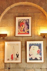 a group of framed pictures hanging on a brick wall at Hôtel Le France in Aubusson