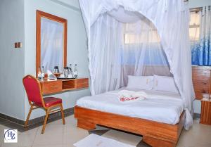 a bedroom with a canopy bed with a chair and a desk at Hotel Zesper in Kisii