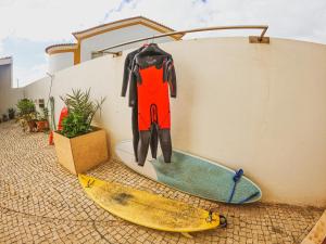 une combinaison de mouillage suspendue sur un mur à côté de deux planches de surf dans l'établissement Cosmos Retreat Baleal, à Baleal