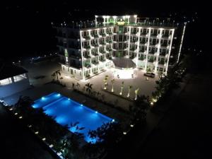 a large building with a pool in front of it at night at Sangkahak Mith Hotel in Kep