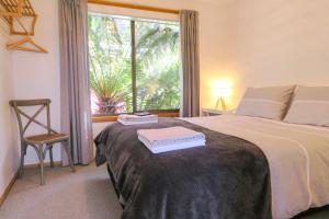 a bedroom with a bed with a window and a chair at Bridgecroft Beach Shack blissful spa retreat for 6 in Port Arthur