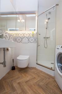 a bathroom with a shower and a toilet and a washing machine at Duży apartament w centrum przy rynku in Białystok