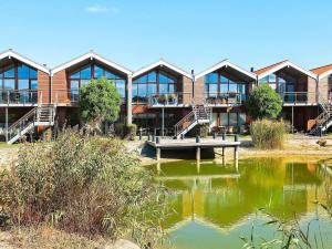 ボーゲンセにある4 person holiday home in Bogenseの池を前に建つ建物