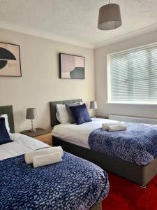 1 dormitorio con 2 camas con sábanas azules y blancas en Delight Marvel- Beech Hurst-3 bedroom house en Maidstone