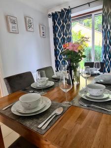 a wooden table with plates and wine glasses on it at Delight Marvel- Beech Hurst-3 bedroom house in Maidstone