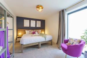布里斯托的住宿－Darlington - 2 Bedroom Luxury Apartment by Mint Stays，一间卧室配有一张床和一张紫色椅子