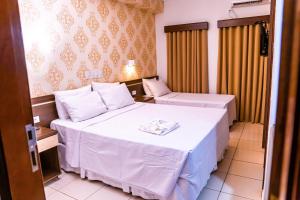 Habitación de hotel con 2 camas con sábanas blancas en Ellus Hotel en Dourados