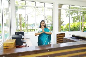 a woman standing in an office with her hands together at Diya Dahara Lake Resort in Tissamaharama