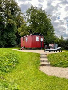 a red shed sitting in a park with a bench at Sheelin Shepherds Hut 2 with Hot Tub in Mountnugent