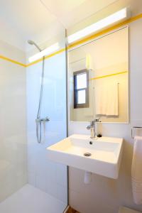 y baño blanco con lavabo y ducha. en Apartamentos Sa Cornisa, en Cala Morell