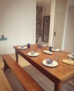 una mesa de madera con platos y vasos. en Maison 3,5km de la plage et proche Mont St Michel en Saint-Broladre