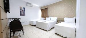 Habitación de hotel con 2 camas y TV en Ellus Hotel, en Dourados
