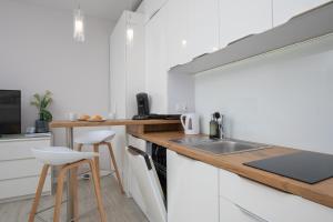 a kitchen with white cabinets and a wooden counter top at Seaside Apartment with Parking - Międzyzdroje Dąbrówki by Renters in Międzyzdroje